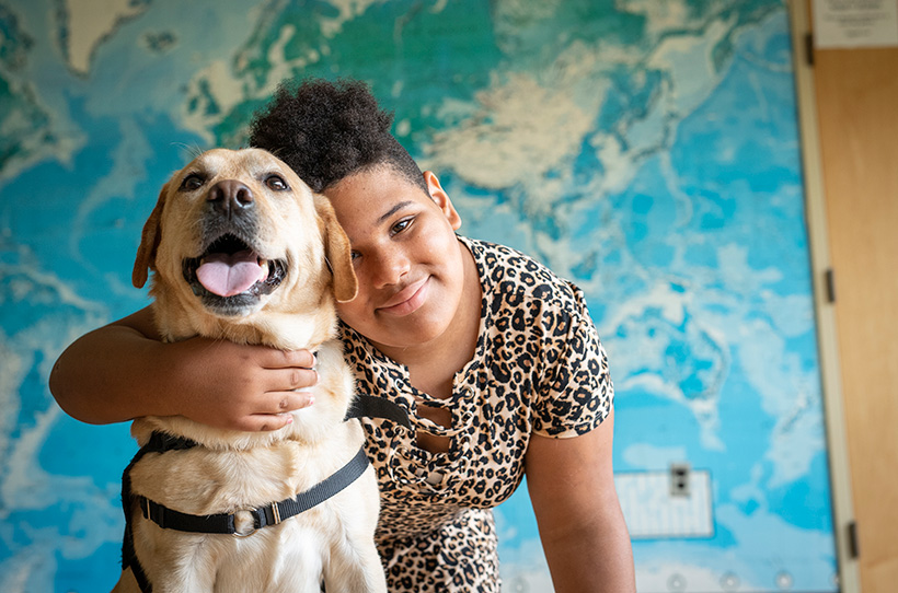 Smiling girl with her arm around a dog
