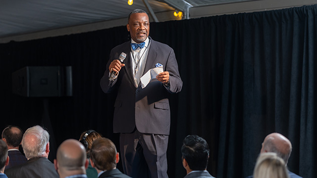 Man in a suit standing delivering a speech
