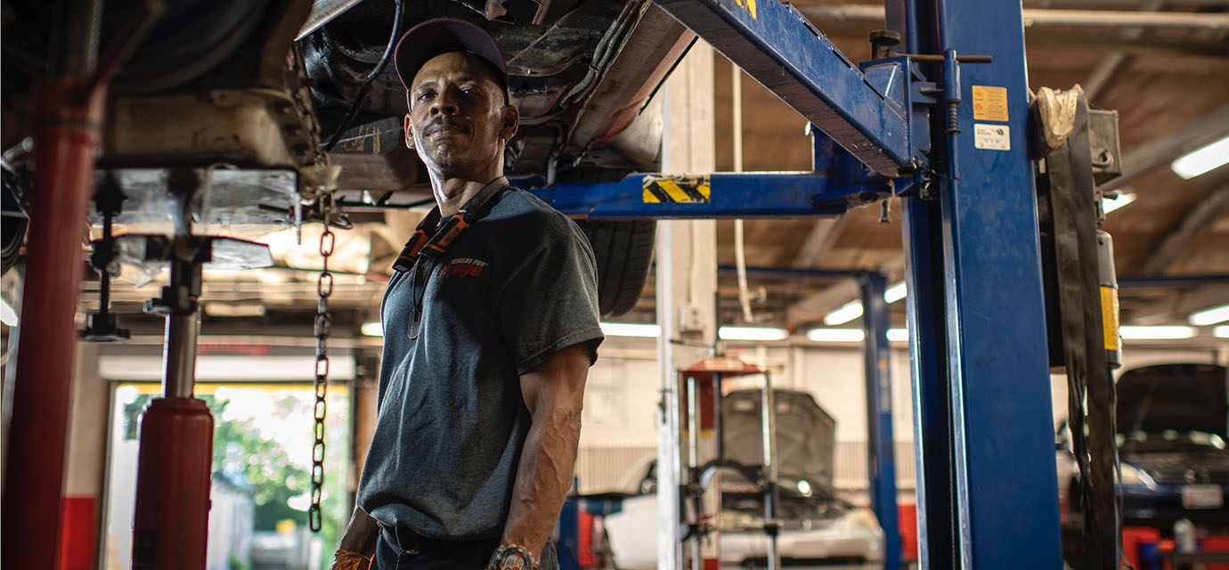 Angled shot of Derek as he works under a suspended vehicle